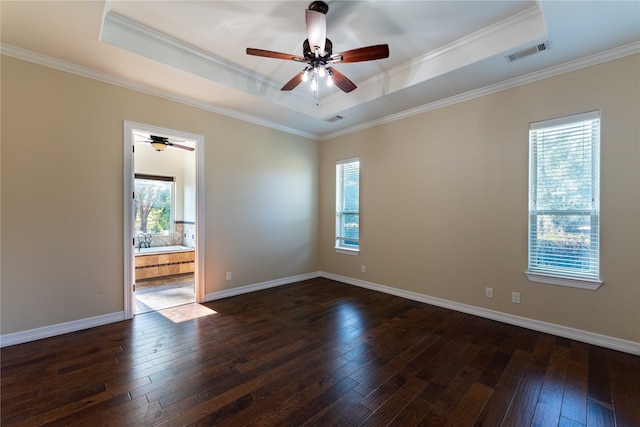 empty room with crown molding, a tray ceiling, and dark hardwood / wood-style flooring