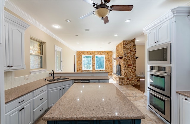 kitchen with white cabinetry, crown molding, sink, and a kitchen island