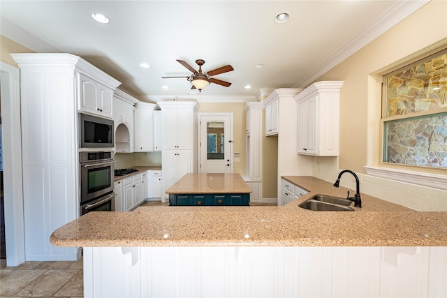 kitchen featuring kitchen peninsula, white cabinetry, a center island, and sink