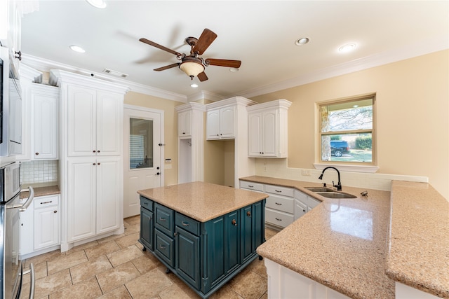 kitchen featuring white cabinets, light stone counters, stainless steel oven, ornamental molding, and sink