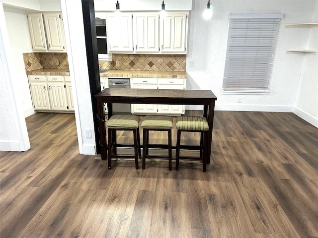 kitchen with backsplash, dishwasher, dark hardwood / wood-style floors, and white cabinets