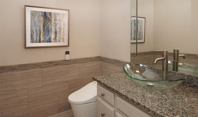 bathroom with toilet, vanity, and tile walls