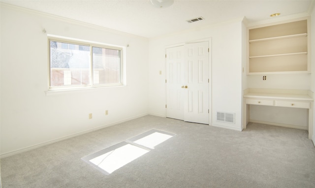 unfurnished bedroom featuring light carpet, crown molding, and built in desk