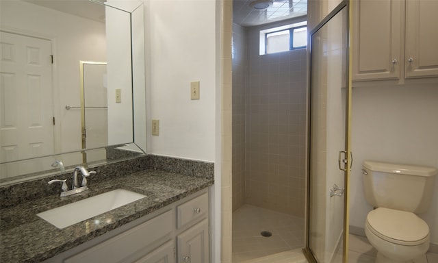 bathroom featuring toilet, tile patterned flooring, vanity, and tiled shower