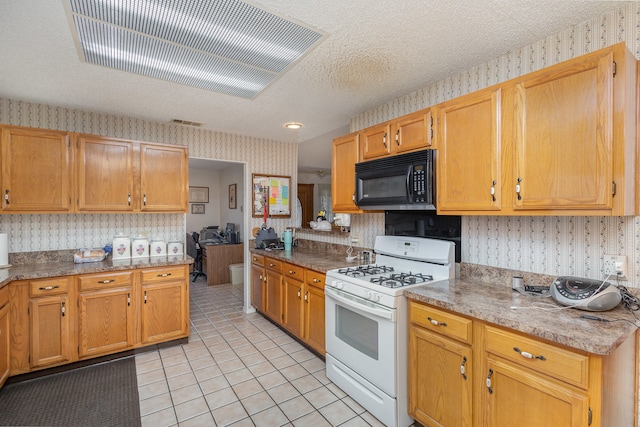 kitchen featuring a textured ceiling, light tile patterned floors, and gas range gas stove