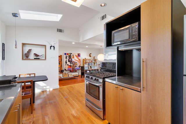 kitchen with pendant lighting, appliances with stainless steel finishes, light hardwood / wood-style flooring, and stainless steel counters