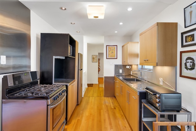 kitchen featuring light brown cabinets, stainless steel counters, light wood-type flooring, stainless steel appliances, and sink