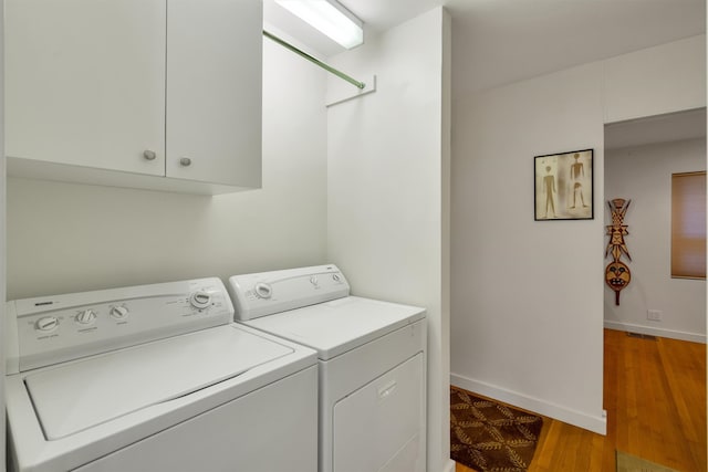 laundry area featuring cabinets, washing machine and clothes dryer, and light wood-type flooring