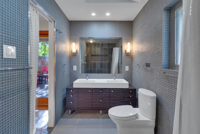 bathroom with toilet, tile walls, walk in shower, vanity, and tile patterned flooring