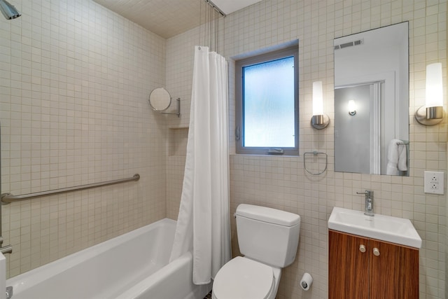 full bathroom with vanity, shower / bath combo, toilet, and tile walls