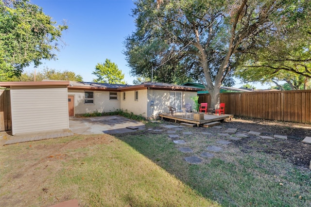 rear view of property with a yard, a deck, and a patio area