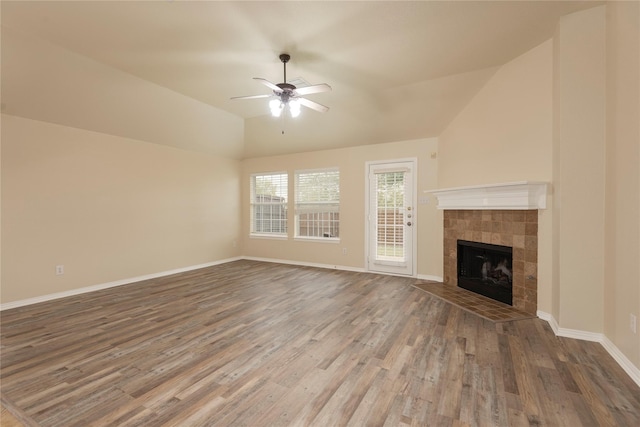 unfurnished living room featuring lofted ceiling, dark wood-type flooring, a tile fireplace, and ceiling fan