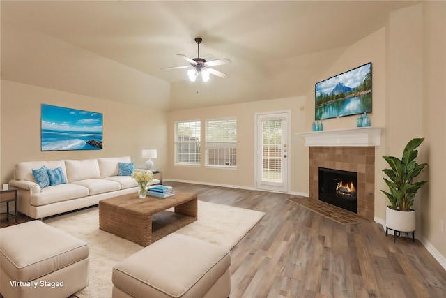 living room featuring ceiling fan, wood-type flooring, lofted ceiling, and a tile fireplace