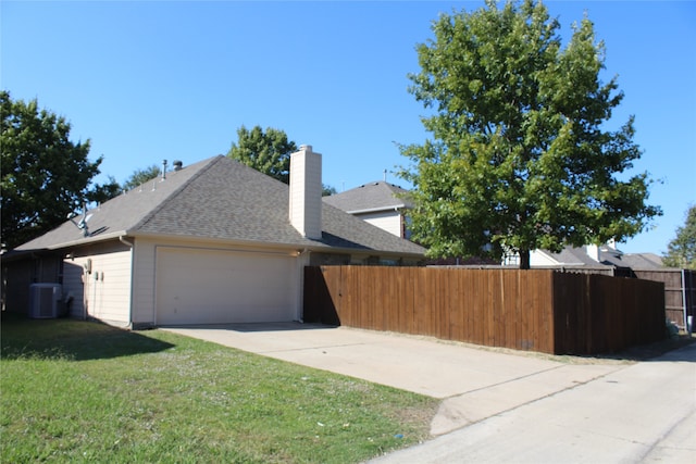 view of side of home with central air condition unit, a yard, and a garage