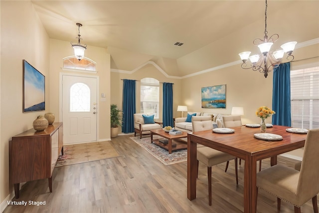 interior space with an inviting chandelier, lofted ceiling, ornamental molding, and light wood-type flooring