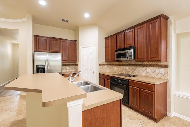 kitchen with tasteful backsplash, black appliances, sink, light tile patterned floors, and a kitchen island with sink