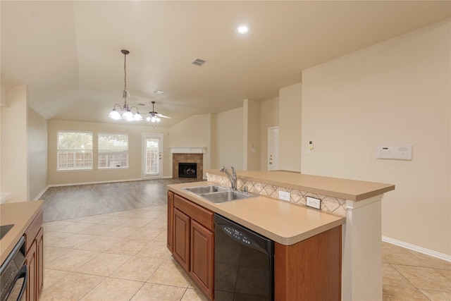 kitchen with a tiled fireplace, an island with sink, vaulted ceiling, dishwasher, and sink