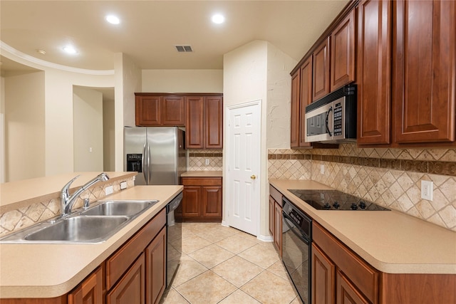 kitchen featuring tasteful backsplash, black appliances, sink, light tile patterned floors, and a center island with sink