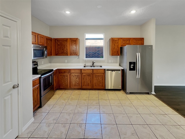 kitchen with appliances with stainless steel finishes, light tile patterned flooring, and sink