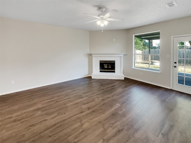 unfurnished living room featuring a textured ceiling, a fireplace, dark hardwood / wood-style floors, and ceiling fan