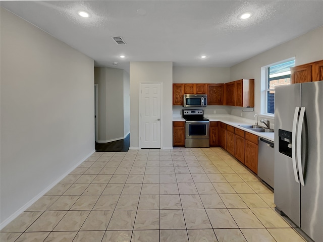 kitchen with sink, appliances with stainless steel finishes, a textured ceiling, and light tile patterned floors