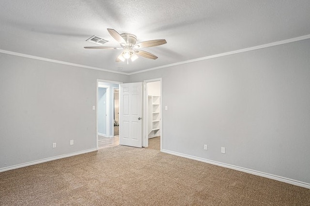 empty room featuring ornamental molding, carpet, a textured ceiling, and ceiling fan