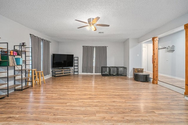 living room with light hardwood / wood-style flooring, a textured ceiling, and ceiling fan