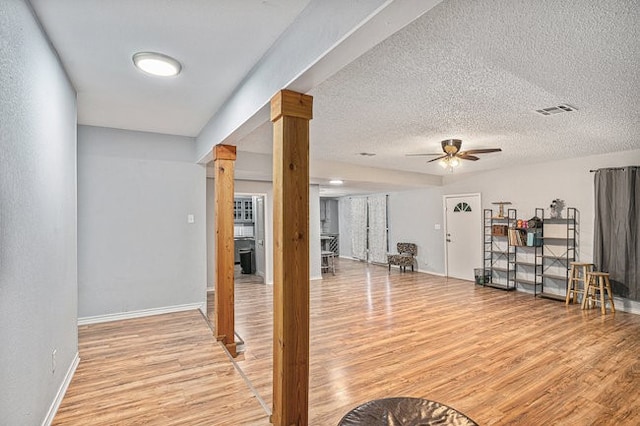 exercise room with ornate columns, light hardwood / wood-style floors, a textured ceiling, and ceiling fan