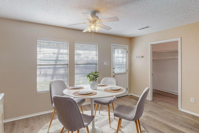 dining room featuring light hardwood / wood-style floors, a textured ceiling, a healthy amount of sunlight, and ceiling fan