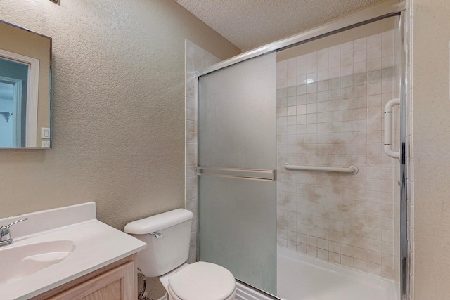 bathroom with vanity, toilet, a textured ceiling, and a shower with shower door