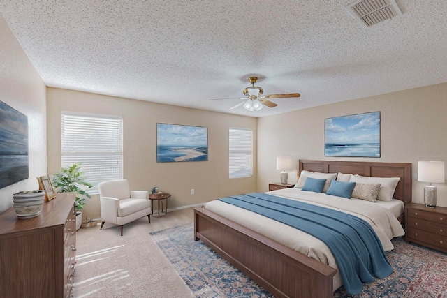 carpeted bedroom featuring ceiling fan, a textured ceiling, and multiple windows