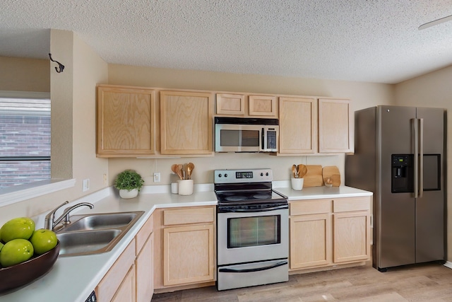 kitchen featuring light brown cabinetry, sink, appliances with stainless steel finishes, and light hardwood / wood-style flooring