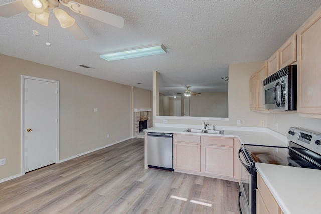 kitchen with appliances with stainless steel finishes, sink, a textured ceiling, kitchen peninsula, and light hardwood / wood-style floors