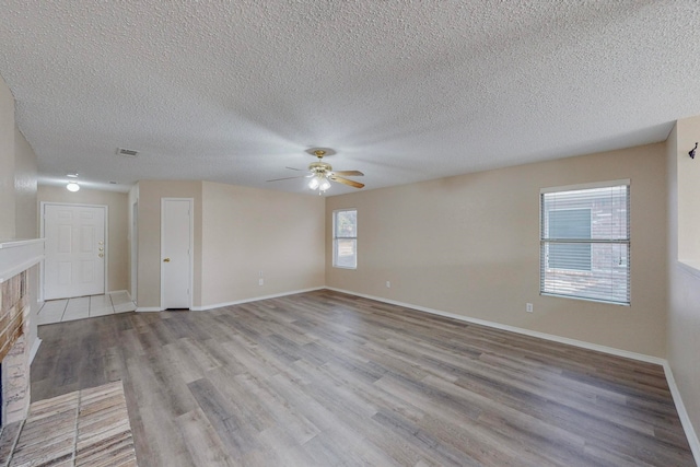 unfurnished living room featuring a textured ceiling, light wood-type flooring, and plenty of natural light