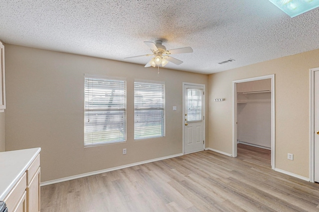 interior space with light hardwood / wood-style flooring, a textured ceiling, and ceiling fan