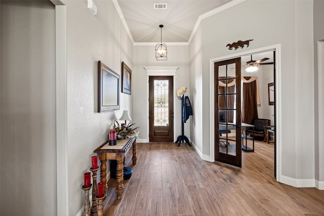 foyer entrance featuring french doors, ornamental molding, ceiling fan with notable chandelier, and light wood-type flooring