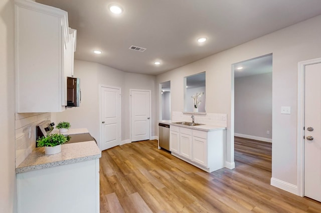 kitchen featuring decorative backsplash, white cabinets, appliances with stainless steel finishes, light hardwood / wood-style floors, and sink