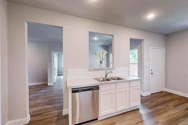 kitchen with wood-type flooring, backsplash, sink, stainless steel dishwasher, and white cabinetry