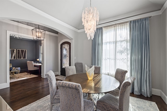 dining area with dark wood-type flooring, a notable chandelier, and crown molding