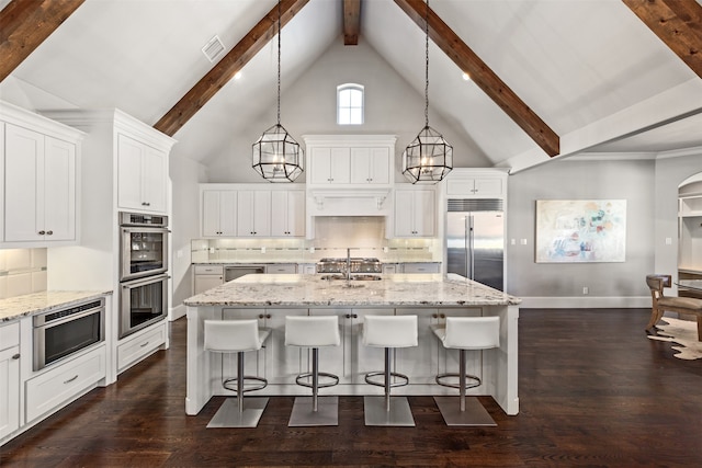 kitchen with a notable chandelier, appliances with stainless steel finishes, decorative light fixtures, and an island with sink