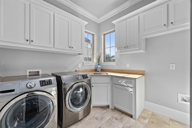 clothes washing area featuring cabinets, ornamental molding, and washer and clothes dryer