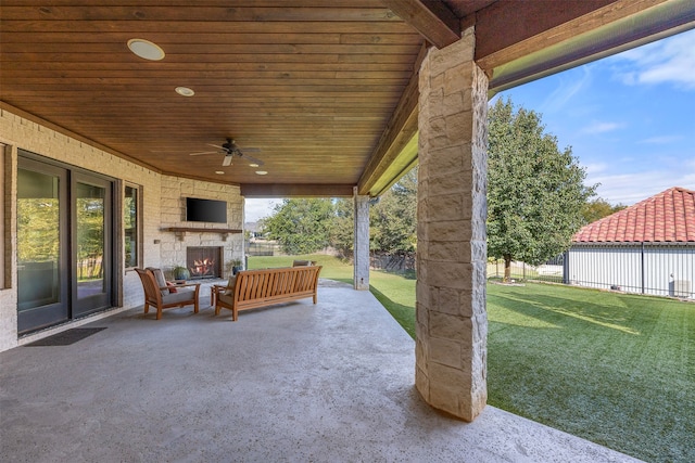 view of patio / terrace with ceiling fan and an outdoor living space with a fireplace