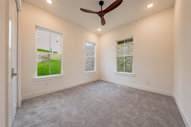 carpeted spare room featuring ceiling fan and a wealth of natural light