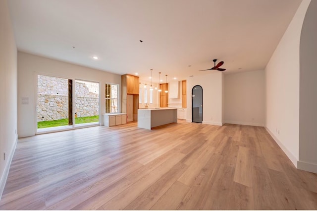 unfurnished living room featuring light wood-type flooring and ceiling fan