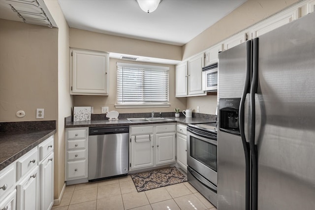 kitchen with appliances with stainless steel finishes, white cabinetry, sink, and light tile patterned floors