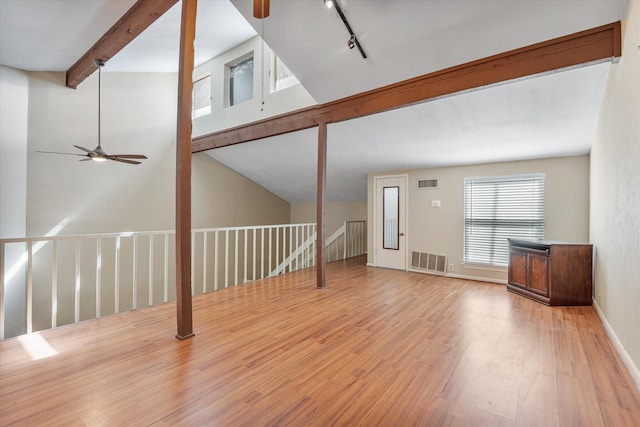 unfurnished living room featuring rail lighting, wood-type flooring, vaulted ceiling with beams, and ceiling fan