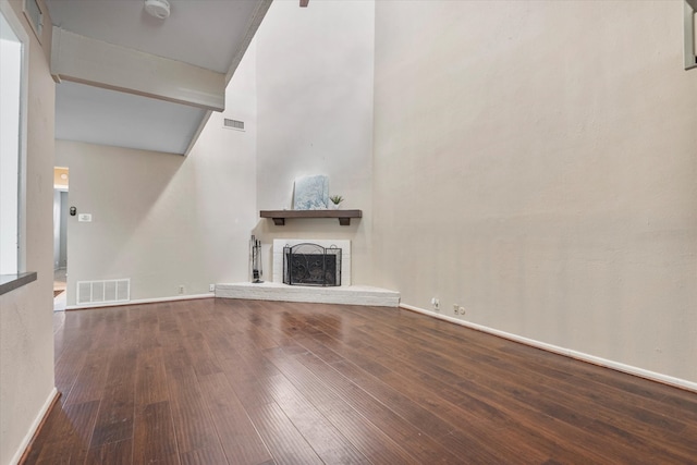 unfurnished living room with a towering ceiling and hardwood / wood-style floors