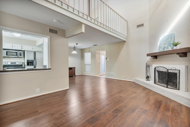 unfurnished living room featuring a towering ceiling, hardwood / wood-style floors, and a fireplace