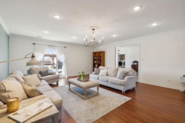 living room featuring dark wood-type flooring, washer and clothes dryer, crown molding, and a chandelier