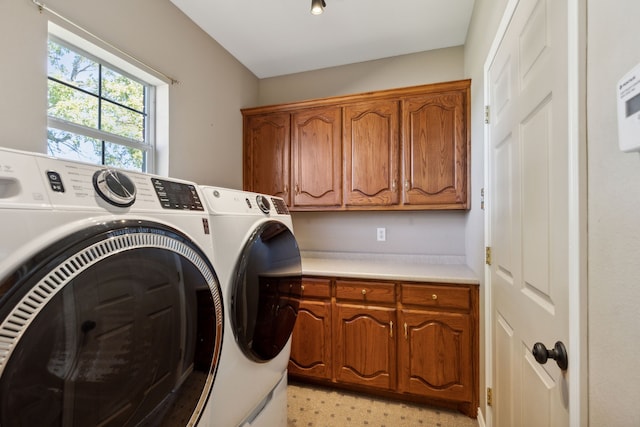 clothes washing area with washer and clothes dryer and cabinets